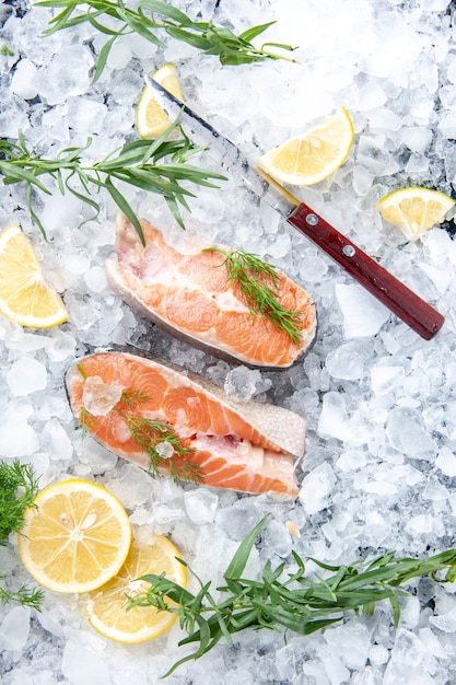 Vista verticale del pesce fresco diviso in due parti con fette di limone su ghiaccio