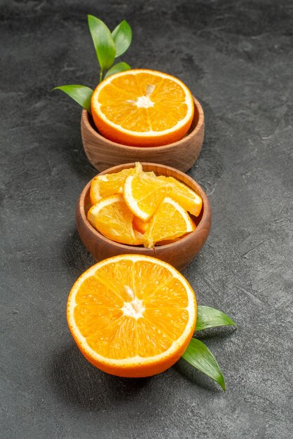 Vista verticale del set di taglio a metà affettato su pezzi di limoni freschi foglie e fiori sulla tavola nera