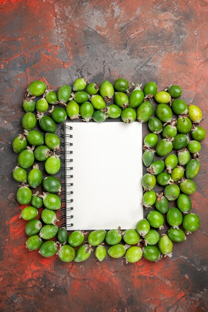 Vista verticale del taccuino tra le piccole bombe vitaminiche feijoas verdi naturali fresche