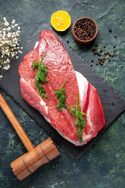 Vista verticale del verde su posate di carne cruda rossa fresca messe su tagliere e martello di legno di limone al pepe su sfondo di colore verde misto nero