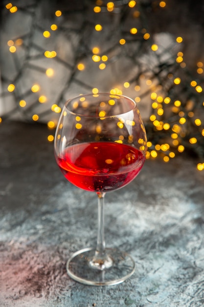 Vista verticale del vino rosso secco in un bicchiere su sfondo grigio