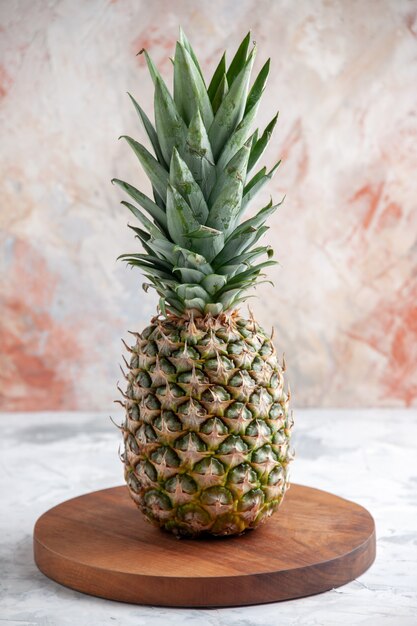 Vista verticale dell'intero ananas dorato fresco su tavola di legno su superficie di marmo