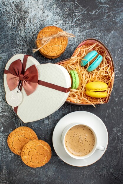 Vista verticale della confezione regalo con macarons e biscotti una tazza di caffè su sfondo scuro ghiacciato