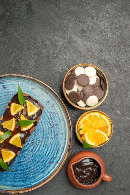 Vista verticale della deliziosa torta decorata con limone e cioccolato con altri biscotti sul tavolo scuro