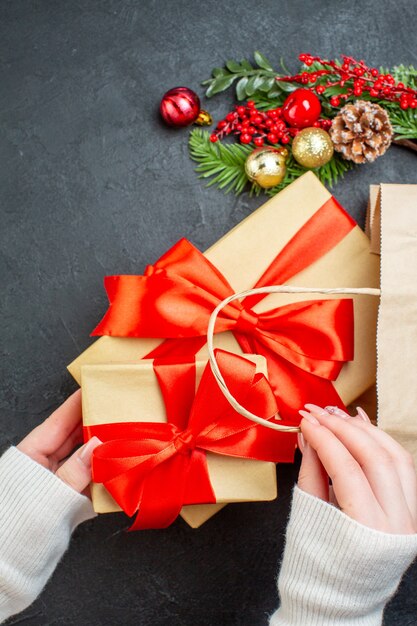 Vista verticale della mano tirando fuori una bella confezione regalo da una borsa su sfondo nero