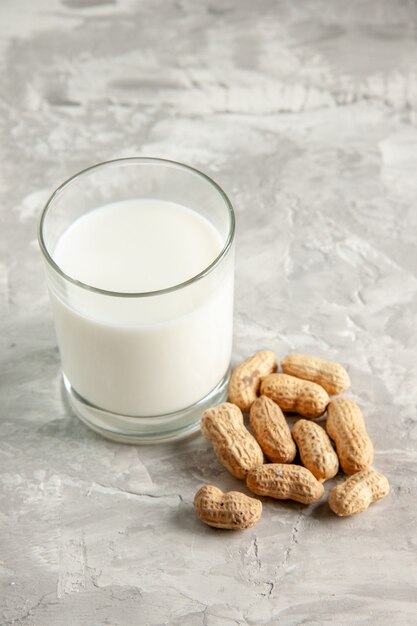 Vista verticale della tazza di vetro piena di latte e frutta secca su sfondo di ghiaccio