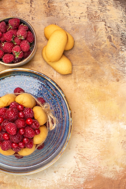 Vista verticale della torta morbida appena sfornata con frutta e biscotti sulla tabella dei colori misti