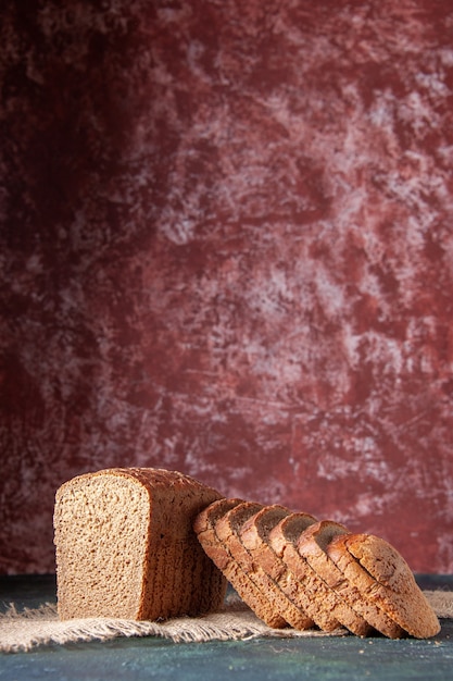 Vista verticale di fette di pane nero su tovagliolo di colore nudo su sfondo di colore marrone rossiccio