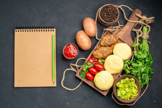 Vista verticale di gustose cotolette verdure tritate un mazzetto di verde per la cena e il taccuino