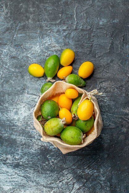 Vista verticale di kumquat freschi in una piccola borsa bianca e su sfondo grigio