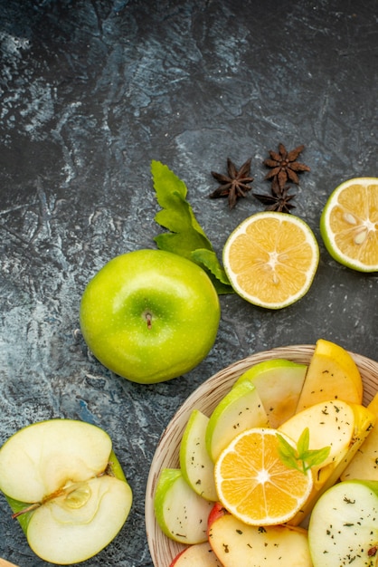 Vista verticale di mele naturali limone su un piatto bianco e arance kumquat lime e cannella sul tavolo scuro