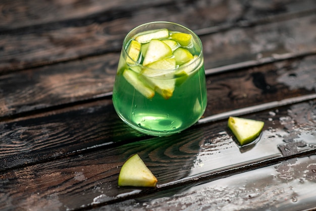 Vista verticale di succo delizioso in un bicchiere con lime di mela su sfondo scuro