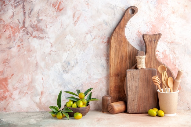 Vista verticale di taglieri in legno marrone di diverse dimensioni e forme in piedi su kumquat a parete in piccoli vasi su parete colorata