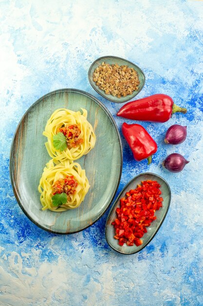 Vista verticale di una cena gustosa con pasta e verdure e carne su sfondo blu