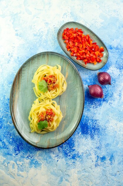 Vista verticale di una cena gustosa con pasta e verdure su sfondo blu