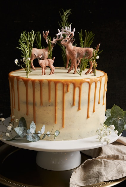 Vista verticale di una torta da sogno con crema bianca e gocce d'arancia con una foresta e renne in cima