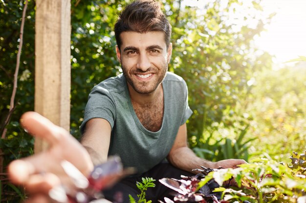 Vita di campagna, natura. Chiuda sul ritratto all'aperto di giovane uomo caucasico barbuto attraente in maglietta blu sorridente