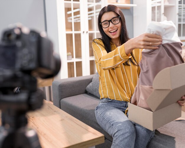 Vlogger femminile a casa con i vestiti unboxing della fotocamera