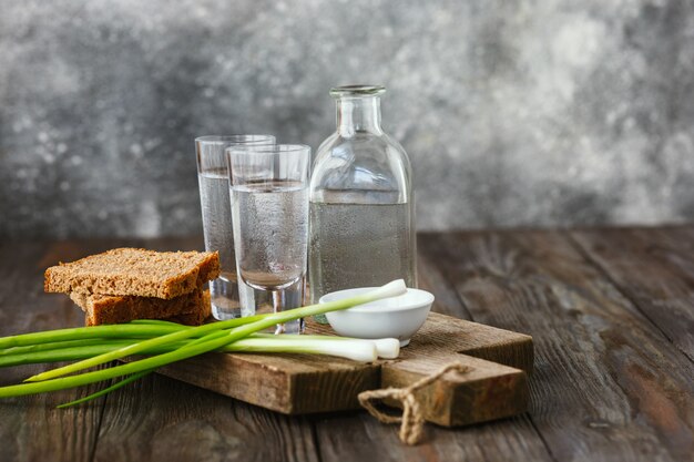 Vodka con cipolla verde, pane tostato e sale sulla tavola di legno