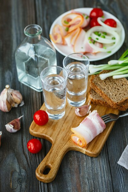 Vodka con lardo e cipolla verde sulla parete in legno.