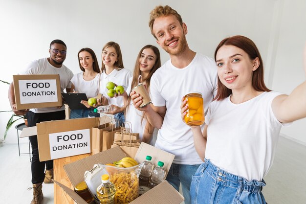 Volontari di smiley che prendono selfie insieme mentre preparano il cibo per la donazione