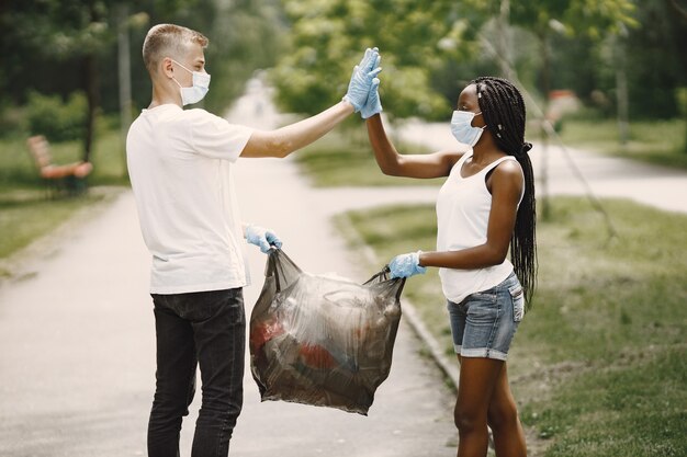 Volontari felici che si danno il cinque l'un l'altro dopo aver completato i compiti. Ragazza afroamericana e ragazzo europeo.