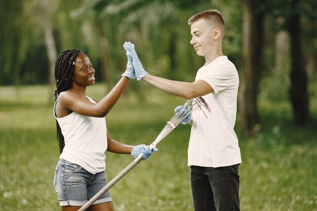 Volontari felici che si danno il cinque l'un l'altro dopo aver completato i compiti. Ragazza afroamericana e ragazzo europeo.