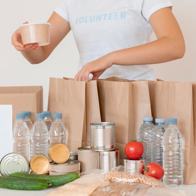 Volontari mettendo cibo cotto e acqua per la donazione in borsa