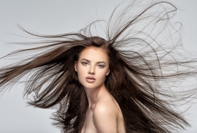 Volto della bella donna con lunghi capelli castani che propone allo studio