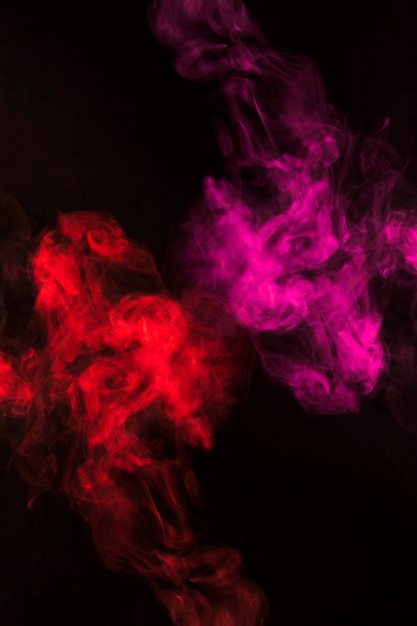 Vorticoso fumo rosso e rosa fumi su sfondo nero