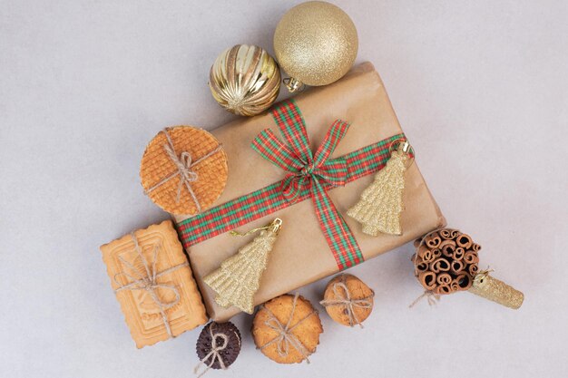 Waffle in corda con regalo e palline dorate di Natale sul tavolo bianco.