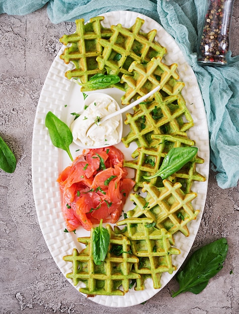 Waffle salati con spinaci e crema di formaggio, salmone in zolla bianca. Cibo gustoso. Vista dall'alto. Disteso