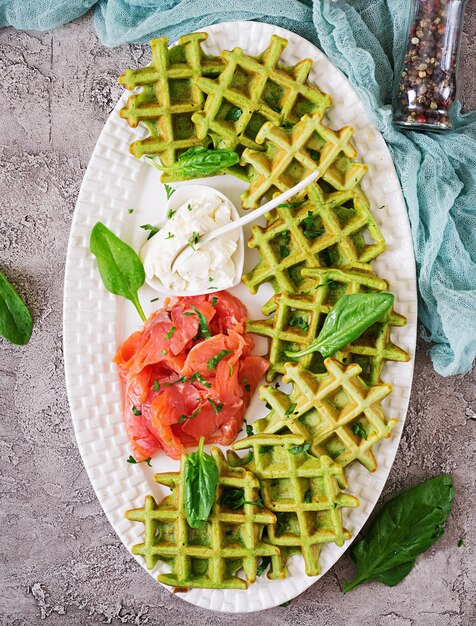 Waffle salati con spinaci e crema di formaggio, salmone in zolla bianca. Cibo gustoso. Vista dall'alto. Disteso