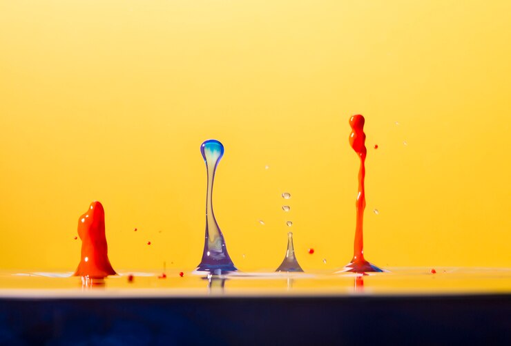 Foto gratuito waterdrops vividi che spruzzano sul giallo