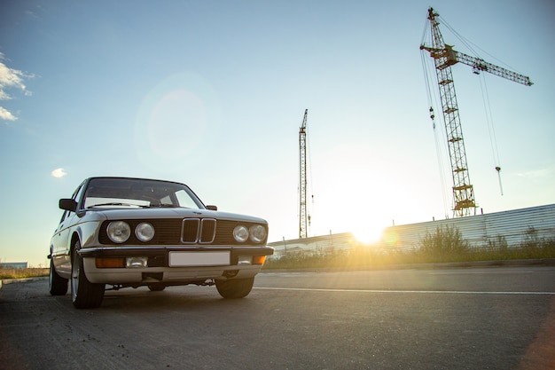 White vintage classic car con fari rotondi sulla strada durante il tramonto