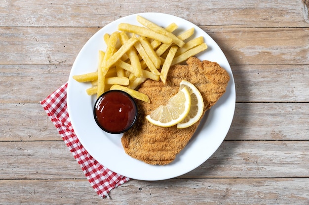 Wiener Schnitzel con patate fritte sul tavolo wooedn