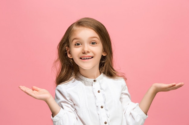 Wow. Bello ritratto frontale femminile isolato sul backgroud rosa dello studio. Giovane ragazza teenager sorpresa emotiva in piedi con la bocca aperta.