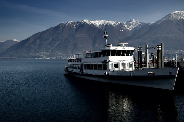 Yacht sul mare circondato da colline ricoperte di verde e neve sotto la luce del sole