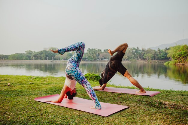 Yoga di addestramento di coppia vicino al lago