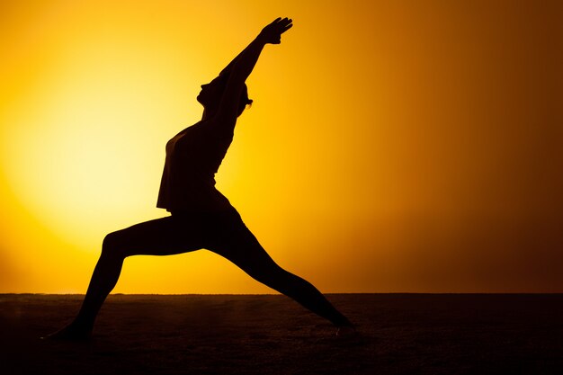 Yoga di pratica della donna alla luce del tramonto