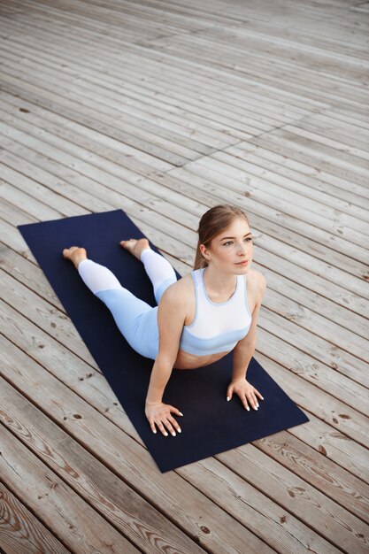 Yoga di pratica della giovane bella ragazza bionda fuori.