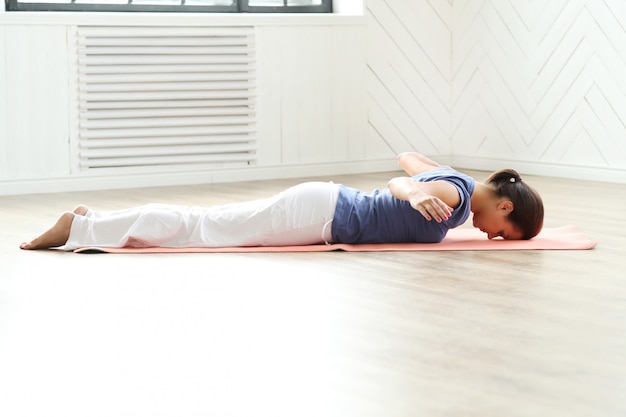 Yoga di pratica della giovane donna su una stuoia di yoga