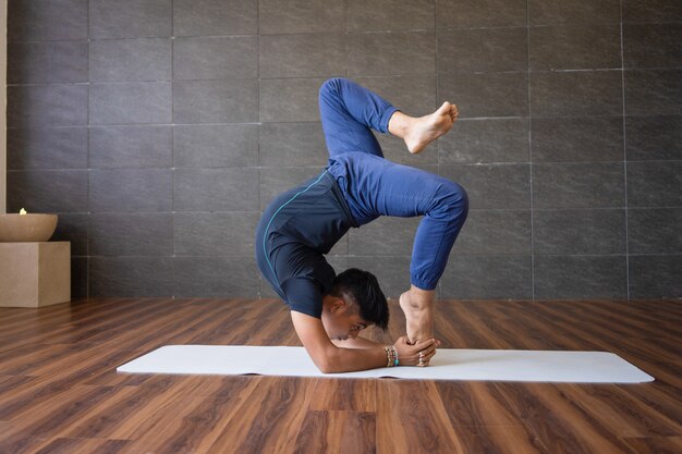 Yogi che fa posa difficile di yoga del supporto della mano in palestra