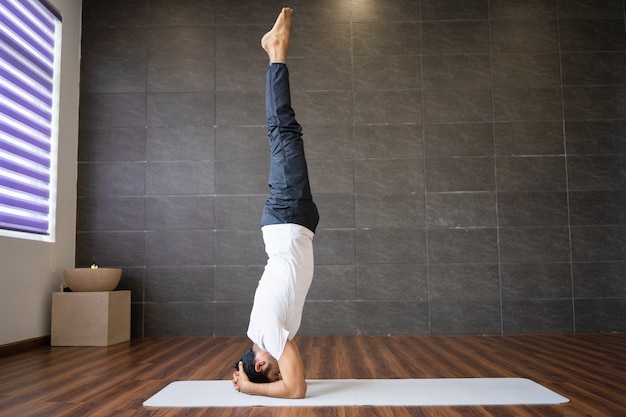 Yogi esperti che fanno yoga in headstand supportato