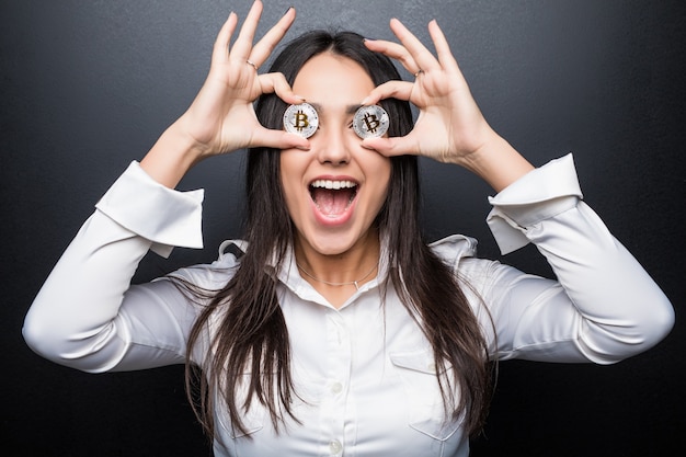 Young business woman scream coprire gli occhi con bitcoin isolato sul muro nero