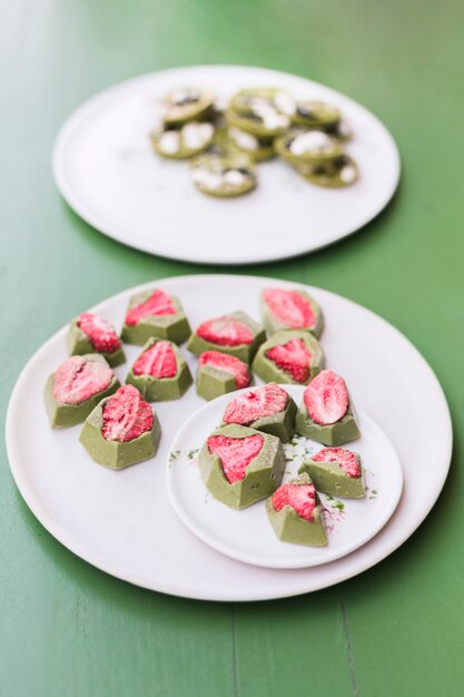 Yummy dessert con fragole su piatti in ceramica bianca sul tavolo verde