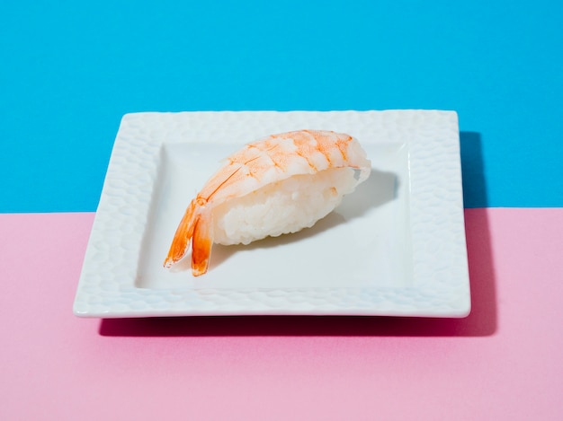 Zolla bianca con i sushi del gambero su una priorità bassa blu e di rosa