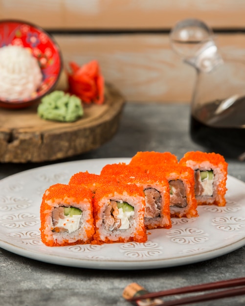 Zolla dei rotoli di sushi con i salmoni, cetriolo coperto in tobiko rosso