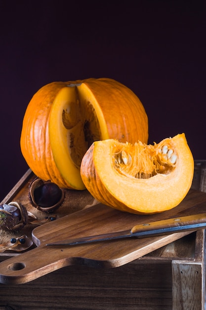 Zucca a fette; koelreuteria paniculata; castagna con coltello sul tagliere di legno