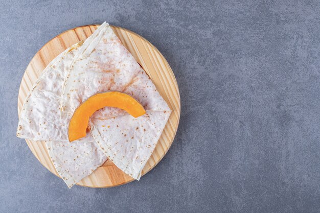 Zucca affettata sul gutap, sul piatto di legno, sulla superficie di marmo.